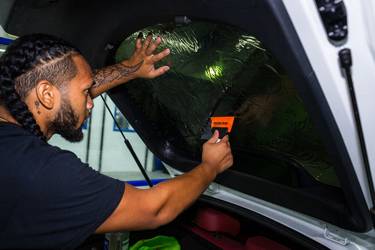 Instalador de Polar Tint Henderson aplicando película de polarizado Nano Ceramic Premium Ceramic a la ventana lateral de un vehículo